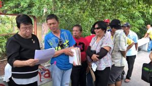 DSWD Secretary Judy M. Taguiwalo reads a document being shown to her by  the leaders of the farmers' organization of  Madaum.  