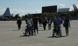 Evacuees with disabilities are assisted by volunteers after disembarking from the C130.