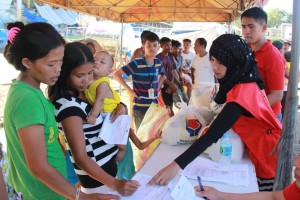 A DSWD staff guides evacuees in signing the distribution list of the family food packs.