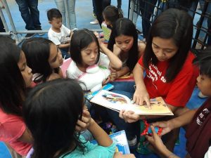 A social worker from the Department of Social Welfare and Development (DSWD) Field Office VII reads a story to children evacuees affected by the landslide in Naga City, Cebu.