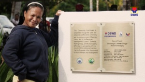 Merlinda Castillo beams with pride as she stands beside the marker for the now finished and usable 0.396 km concrete road in Purok Saging, Barangay Libo-o, Ronda, Cebu. The sub-project was made possible through the Department of Social Welfare and Development's (DSWD) Kapit-Bisig Laban sa Kahirapan Comprehensive and Integrated Delivery of Social Services (KALAHI-CIDSS).